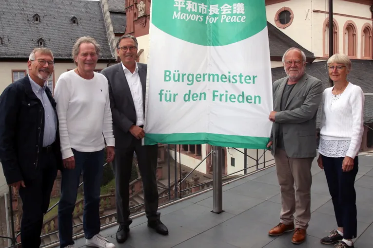 Vier M&auml;nner und eine Frau mit der Mayors-for-Peace-Flagge.